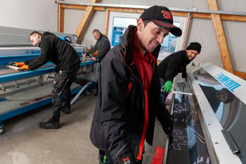 Vier Männer arbeiten in einer Werkstatt an großen Maschinen, um Bleche zu biegen und zu formen.